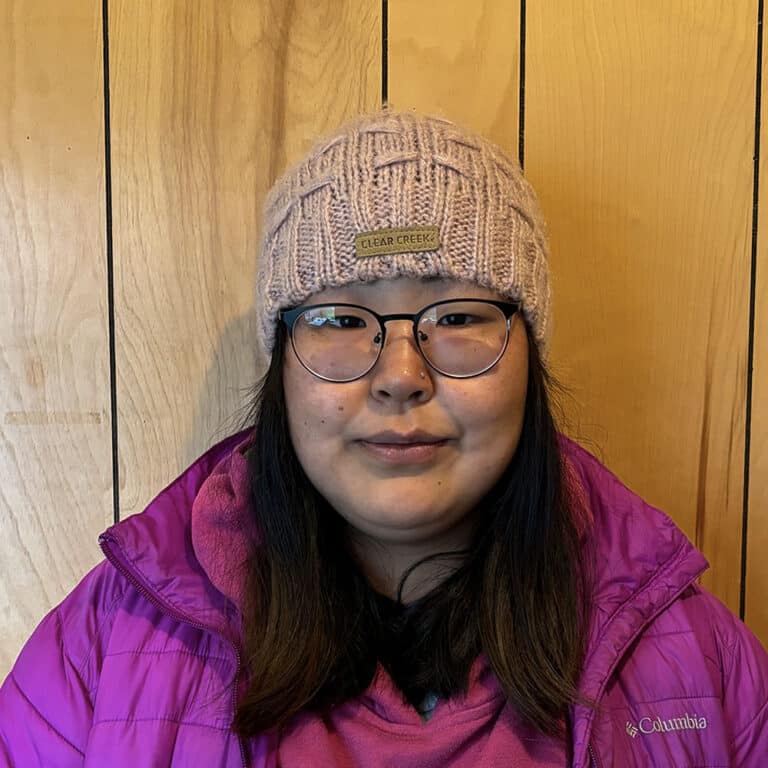 Woman wearing a hat, glasses, and a Pink Columbia coat smiling