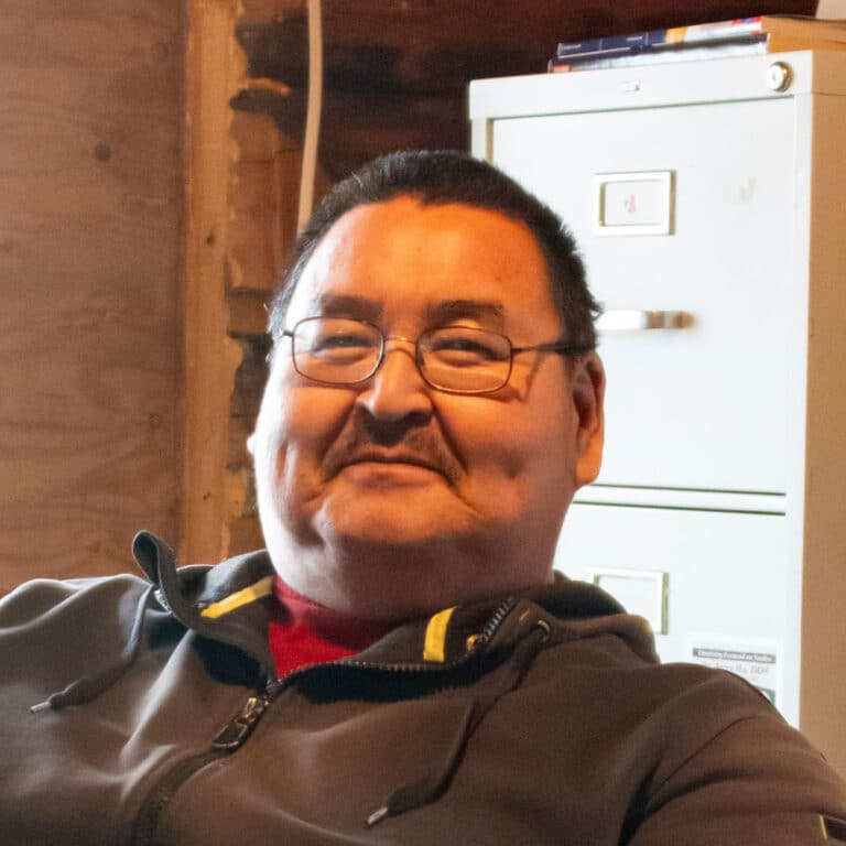 Man wearing glasses and a hoodie smiling