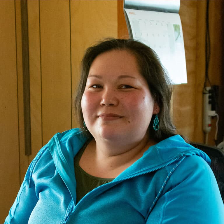 Woman wearing blue earrings and a blue hoodie smiling