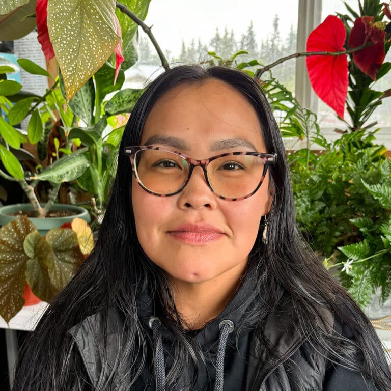 Woman with glasses in front of plants inside